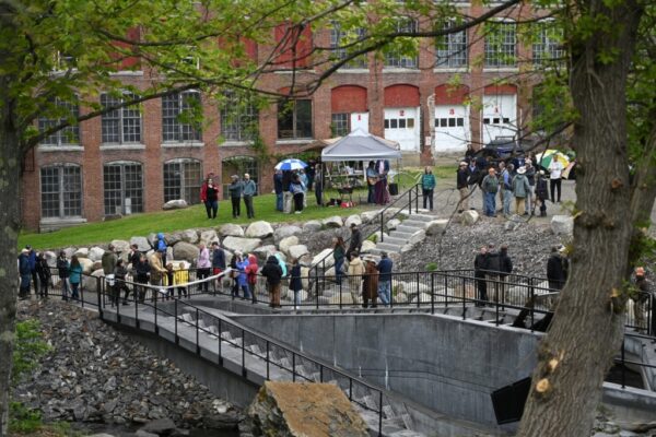 18753# 01alewives VASSALBORO, MAINE May 19, 2022. People gather at a completed Denil fishway during an event that celebrated the project completion along Outlet Stream that flows past the Olde Mill Place at 934 Main St. in Vassalboro, Maine Thursday May 19, 2022. The event, hosted by Maine Rivers, featured a ribbon cutting by Maine Governor Janet Mills. The completed project clears the migration path up China Lake Outlet Stream for the alewives. The project is designed to restore river access and encourage the return of the alewives. (Morning Sentinel/Rich Abrahamson)